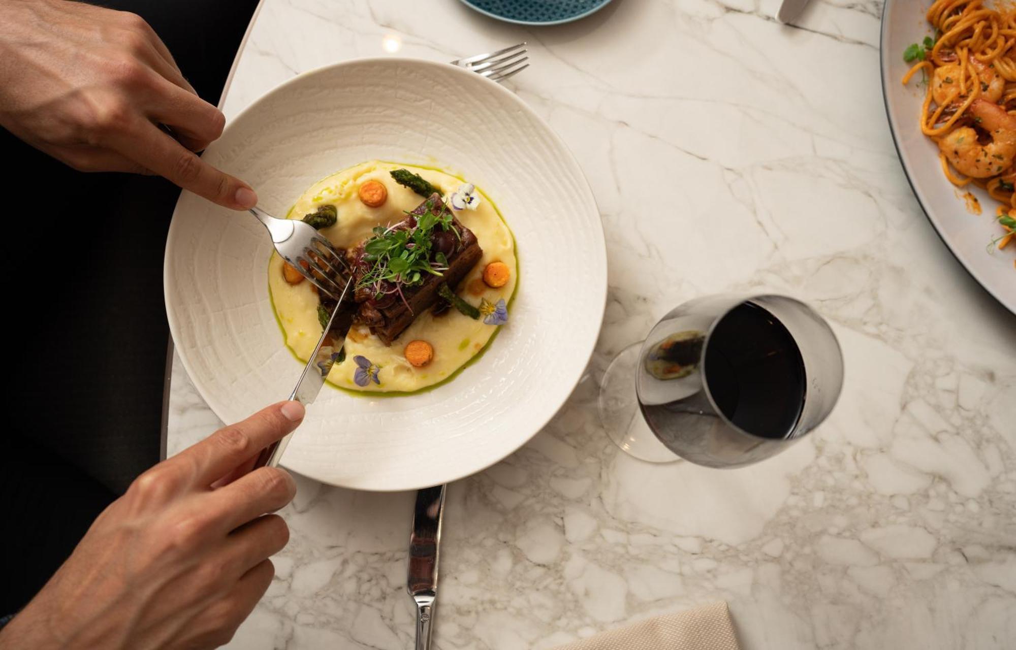 Address Istanbul Hotel Kültér fotó A person using a fork to cut into a meal